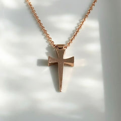 Rose gold cross necklace on a white background