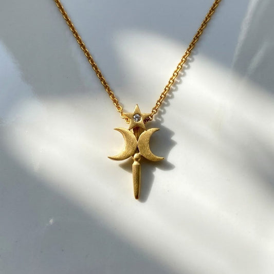 Gold necklace with a star and moon pendant on a white background