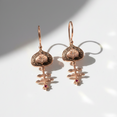Rose gold earrings with intricate designs on a light background