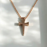 Rose gold cross necklace on a white background