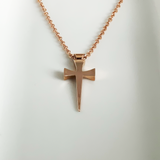 A rose gold cross pendant necklace displayed against a white background.