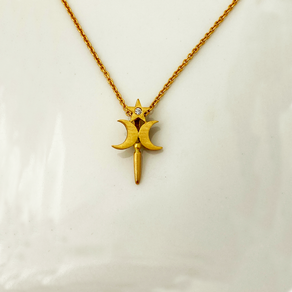 A gold-colored pendant featuring a star-shaped design with a natural brilliant diamond in the center, displayed against a white background.