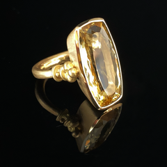 A golden ring with a large natural beryl stone set in a matte solid 18-karat gold band, featuring an Etruscan weighted shank design with a unique ball collar and triad motif.