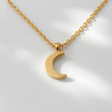 Gold crescent moon necklace on a light white background