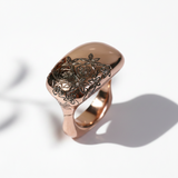 A rose gold ring with a nature-inspired floral motif hand-carved on the top surface.