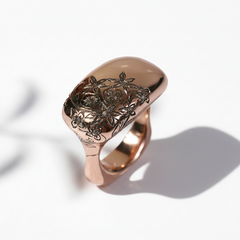 A rose gold ring with a nature-inspired floral motif hand-carved on the top surface.