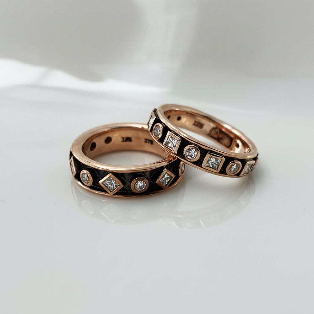 Two rose gold bands featuring geometric patterned detailing and embedded with round and princess cut diamonds set against a blackened background.