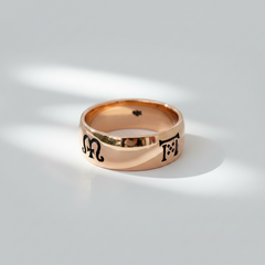 A handcrafted rose gold band ring with engraved symbols representing the four seasons on its surface.