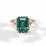 An emerald-cut tourmaline ring with a rose gold band and a white gold bezel, set with smaller tourmalines around the main stone.