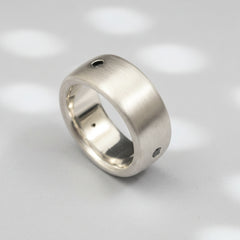 A matte-finished white gold ring with three natural black diamonds set in a row.